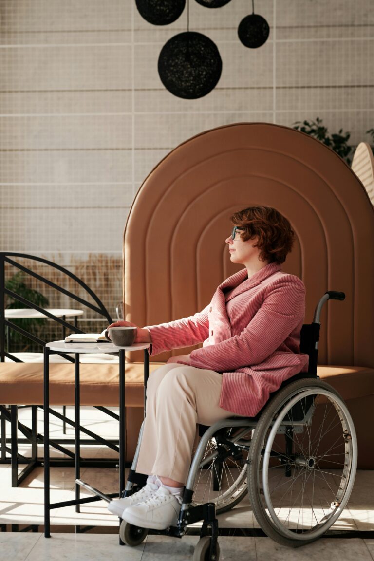 A businesswoman in a wheelchair sits at a table enjoying coffee in a modern cafe.